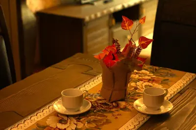 a table with two cups and a vase with flowers at Апартамент Орфинда- Pamporovo in Pamporovo