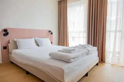 a white bed with towels on it in a bedroom at Студио 8 Уютна Почивка in Hisarya