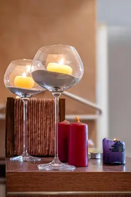 two wine glasses sitting on a table with candles at Villa TIANA Bansko 7-Bedroom Luxury Chalet in Bansko