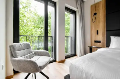 a bedroom with a bed and a chair and a window at Hotel HAYASHI - Free Parking and Fitness in Sofia