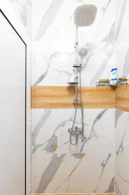 a shower in a bathroom with marble walls at City Retreat with Local Charm in Plovdiv