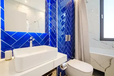 a blue tiled bathroom with a sink and a toilet at The House of Pom in Plovdiv