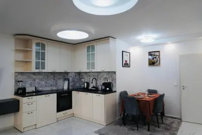 a kitchen with white cabinets and a table with chairs at Top Central Apartment 14 in Sofia