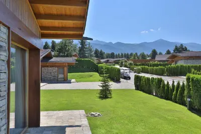 a backyard with a green lawn and a house at Emily Pirin Golf in Razlog