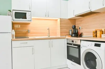 a kitchen with white cabinets and a washer and dryer at Armand de Sanelle in Sofia