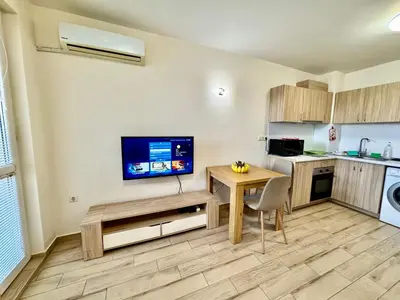 a kitchen with a table and a tv on a wall at Joyful Studio in Sofia