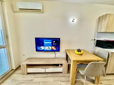 a living room with a table and a tv on a wall at Joyful Studio in Sofia