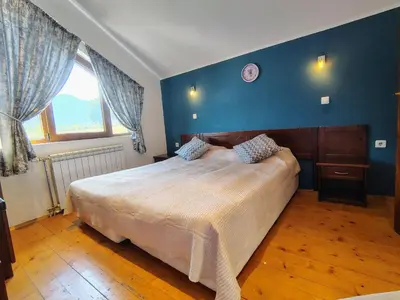 a bedroom with a large bed and a blue wall at Fairytale Cottage in Redenka in Razlog