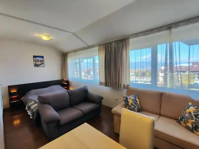 a living room with a couch and a large window at Bansko Tower Cozy Studio with Mountain View in Bansko
