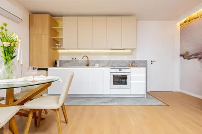 a kitchen with white cabinets and a table with chairs at Stylish City Escape 1BD Apartment in Plovdiv in Plovdiv