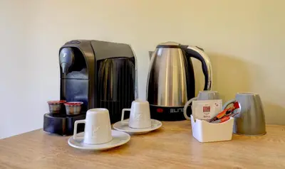 a coffee maker and cups on a wooden table at Hotel Borovets Palace in Borovets