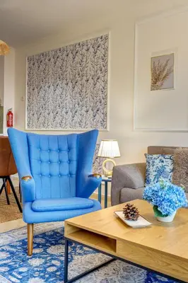 a living room with a blue chair and a table at Ski Slope Getaway at Grand Monastery in Pamporovo