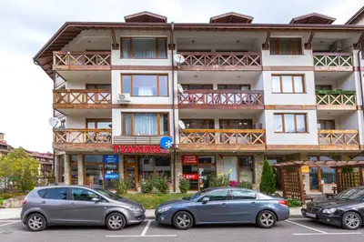 two cars parked in a parking lot in front of a building at Cozy and warm apartment with a separate bedroom in Bansko