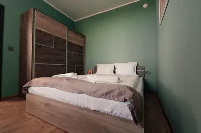a bedroom with a large bed with a wooden headboard at Rila Zen Apartment in Samokov