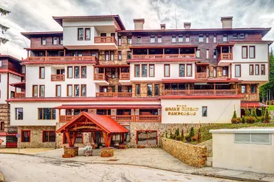 a large white building with a red roof at Grand Resort Pamporovo Apartments in Pamporovo