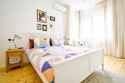 a white bedroom with a bed with a colorful comforter at Boho Gem in Sofia