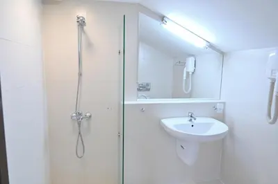 a white bathroom with a shower and a sink at Хотел Елица in Bansko