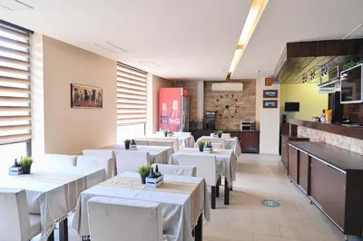 a dining room with white tables and white chairs at Хотел Елица in Bansko