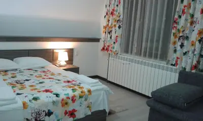 a bedroom with a bed and a chair and a window at Къща за гости Семейство Петрови in Kalofer