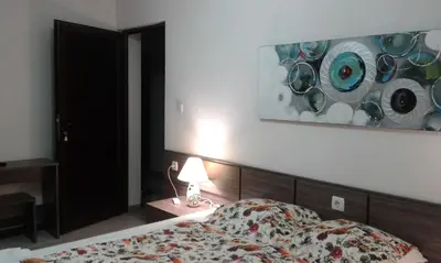 a bedroom with a bed and a painting on the wall at Къща за гости Семейство Петрови in Kalofer