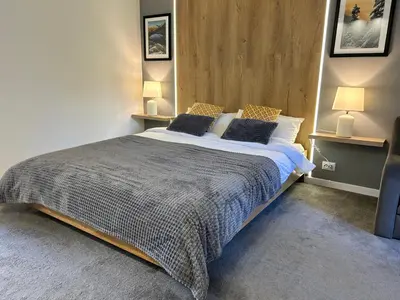 a bedroom with a large bed with two lamps at Devonshire Lodge Chalet in Bansko