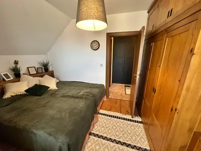 a bedroom with a large bed and a clock on the wall at Murphys Lodge panorama apartment in Bansko