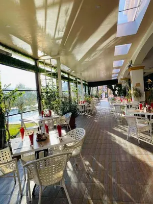 a restaurant with white tables and chairs and windows at Hotel Paradise in Ognyanovo