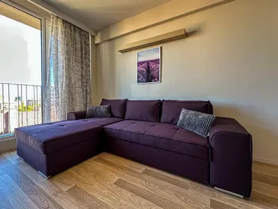a purple couch in a living room with a window at Quiet & Comfortable Urban Retreat in Sofia
