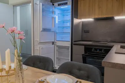 a kitchen with a table with chairs and an open refrigerator at Luxury & Modern Apartment - Rowing Canal Plovdiv in Plovdiv