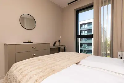 a bedroom with a bed and a mirror and a window at Royal Garden apartment with Private Parking in Plovdiv