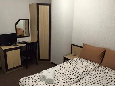 a hotel room with a bed and a desk at Семеен хотел Гингеръ in Pamporovo