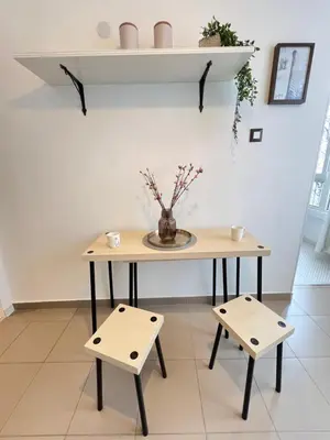 a table with two stools and a vase with flowers at Bogota Central Apt w Office Space and Wifi near Metro in Sofia