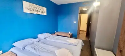 a blue bedroom with a large bed with white sheets at Julia rooms in Sofia
