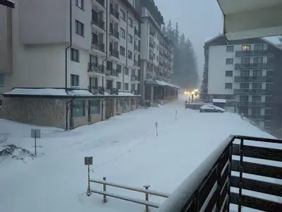 a snow covered street with buildings and a parking lot at Sunny Mountain View Villa Kometa in Pamporovo