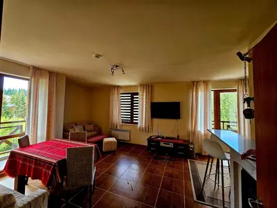 a living room with a table and a television at Captain's Apartment in Pamporovo