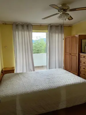 a bedroom with a bed with a ceiling fan and a window at Райска тишина in Zlatitsa