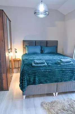 a bedroom with a large bed with a blue blanket at Two Modern Apartments in One Building by SI Stay in Bansko