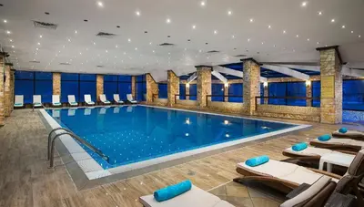a large swimming pool with lounge chairs in a building at Apartment VIP in Hotel Sveti Spas in Velingrad