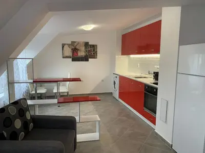 a kitchen with red cabinets and a living room at Stylish 1BR near Centre in Sofia
