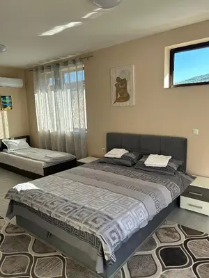 a bedroom with two beds and a flat screen tv at Семеен хотел Струма in Boboshevo