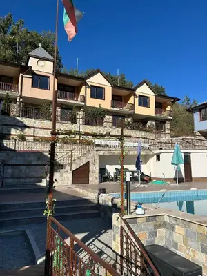 a building with a swimming pool and a building with a flag at Семеен хотел Струма in Boboshevo