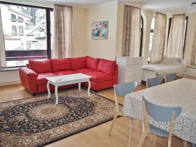 a living room with a red couch and a table at Elit Pamporovo Apartments in Pamporovo