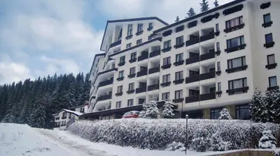 a large white building with snow on the ground at Elit Pamporovo Apartments in Pamporovo