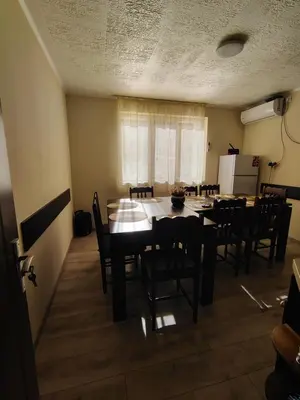 a dining room with a table and chairs and a refrigerator at Вила Владислава - стаи за гости in Cherni Vit