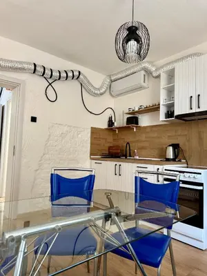 a kitchen with a glass table and blue chairs at Atelier-apartament in Sandanski
