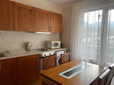 a kitchen with wooden cabinets and a table with a microwave at Cedar Lodge Apartament - Gondola in Bansko