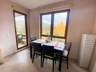 a dining room with a table and chairs and a window at Green Life Private Apartment D27 in Bansko