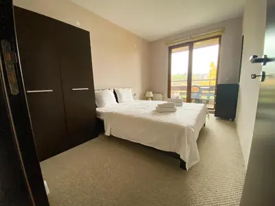 a bedroom with a bed with white sheets and a window at Green Life Private Apartment D27 in Bansko