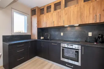 a kitchen with black cabinets and a sink and a stove at Panoramic View Cozy 1BR Apartment in Plovdiv