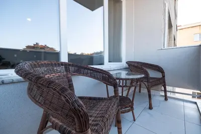 three wicker chairs and a table on a balcony at Panoramic View Cozy 1BR Apartment in Plovdiv